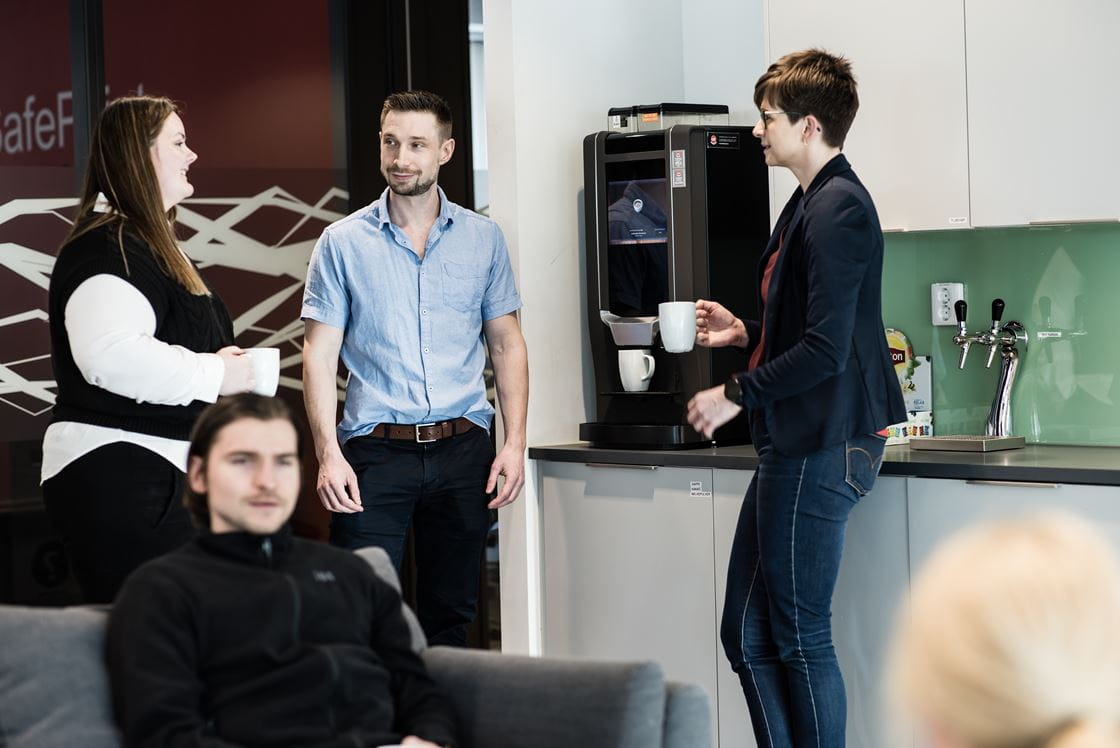 Loomisansatte som diskuterer i pauserommet ved kaffemaskina